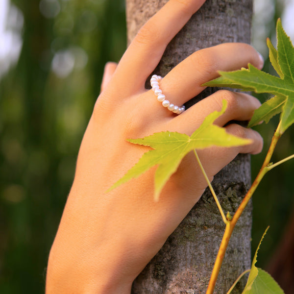Vue porté sur la main de la Bague élastique composée de petites perles de culture d’eau douce blanches, taille adaptable à tous les doigts.