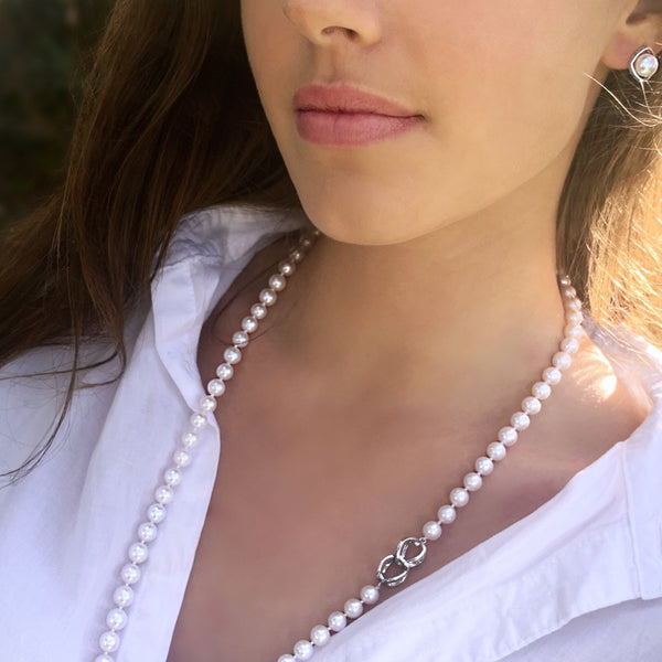 Vue sur mannequin du collier papillon porté de façon simple perles de culture semi rondes 8 mm couleur blanc nacré longueur 72 cm  fermoir original en argent 925 et présenté  ici avec les boucles d'oreilles perle sur cadre d'argent neige.